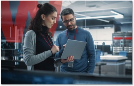 Co-workers looking at a laptop together standing in from of a large red W