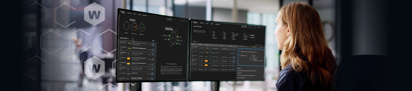 Blonde woman looking at two monitors showing WatchGuard MDR screens